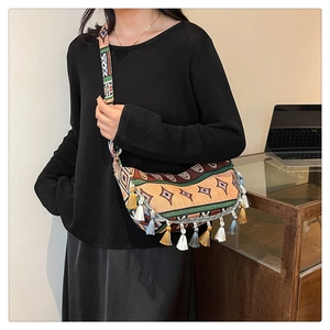 Detail of bohemian geometric pattern fabric and long colorful tassels on crossbody bag
