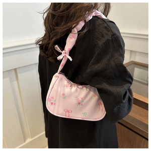Detailed close-up of a pink strawberry and floral print shoulder bag with bow detail