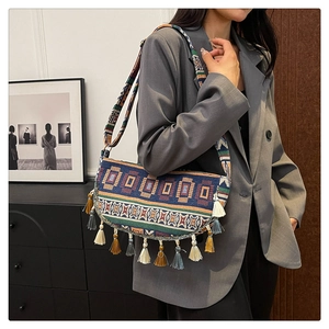 Detailed close-up of a bohemian woven shoulder bag featuring colorful tassels and ethnic patterns