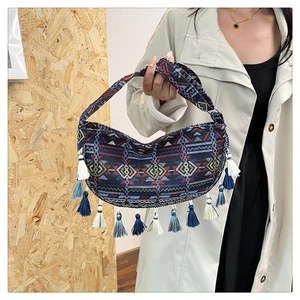 Detail of ethnic crescent crossbody bag with colorful geometric patterns and long tassels