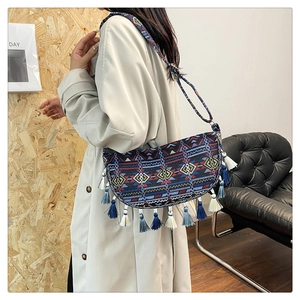 Close-up of bohemian tassel shoulder bag with colorful ethnic patterns on a model
