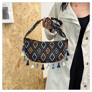 Detail of bohemian crescent bag featuring ethnic jacquard patterns and tricolor fringes