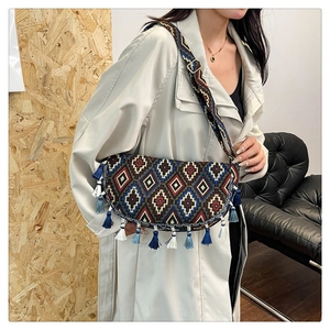 Detail of bohemian shoulder bag with geometric embroidery and blue tassel accents