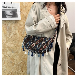 Close-up of bohemian tassel saddle bag with ethnic embroidery and woven strap