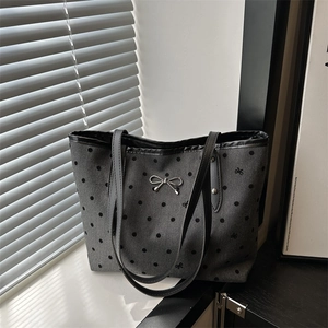 Sac cabas gris à pois avec détail nœud métallique sur le rebord d'une fenêtre