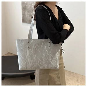 Detail of silver tote bag with pleated texture and metallic finish on shoulder straps