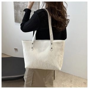Close-up of a white tote bag with cloud texture and metallic rivet reinforcements