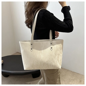 Creamy white tote bag featuring natural leather texture and stylish black metal rivets