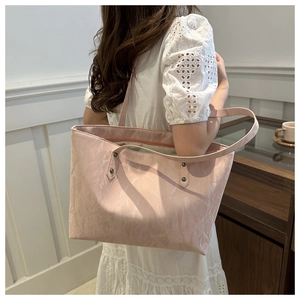 Detail of light pink tote bag with stone texture finish and metal rivet strap accents