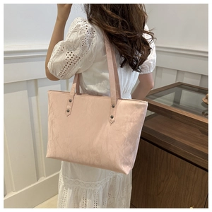 Detail of light pink tote bag featuring glossy wrinkled leather and vintage rivets