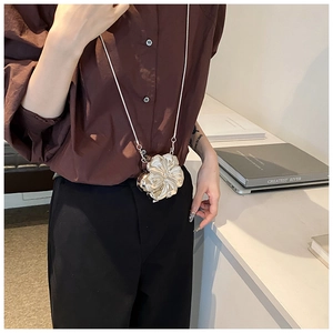 Silver flower metal mini chain bag accessory worn with a dark brown shirt and trousers