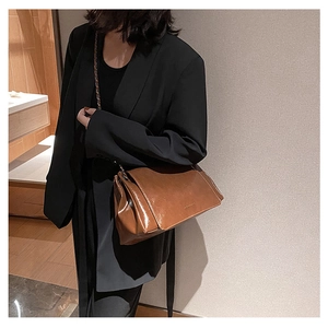 Caramel brown leather shoulder bag featuring metal chain strap and pleated side detail