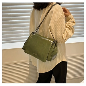 Detail of green oil wax leather crossbody bag with chain strap and accordion side design