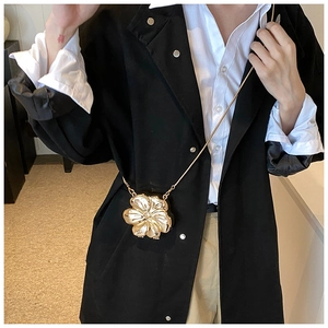 Detail of a golden flower-shaped mini decorative crossbody bag with a slim metal chain