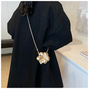 Detailed view of a gold flower shaped acrylic evening bag with a metallic chain strap