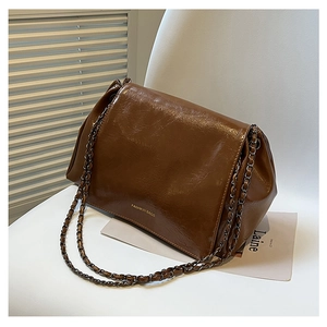 Detail of vintage brown oil wax leather shoulder bag with golden text and chain strap