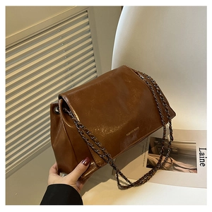 Close-up of caramel leather shoulder bag with silver chain strap and metal buckle
