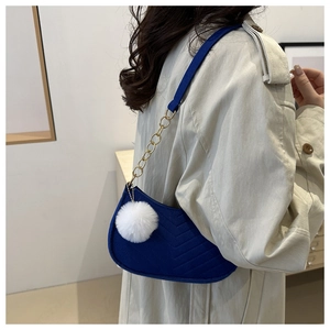 Dettaglio borsa a spalla blu navy con trapuntatura a V catena dorata e pompon bianco