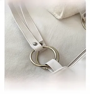 Detailed close-up of the silver metal ring connector on a white leather tote bag handle