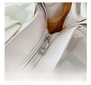 Detail shot of the smooth silver zipper and interior lining of the white tote bag