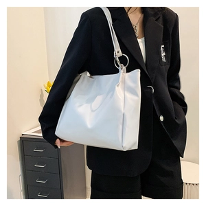 Detail of white leather tote bag with decorative oversized silver metal ring and wide strap