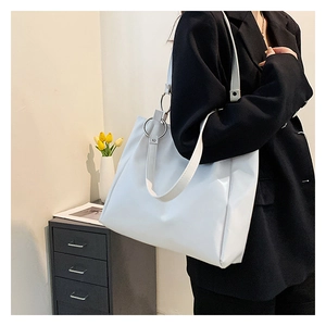 Detail of white leather tote bag with silver metal ring buckle worn on shoulder