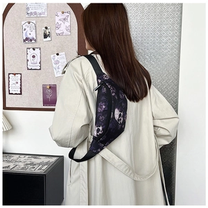 Close-up of chest bag with purple floral and skull print worn over a beige coat