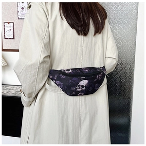 Close-up of stylish waist bag featuring skull and floral prints on a dark purple fabric