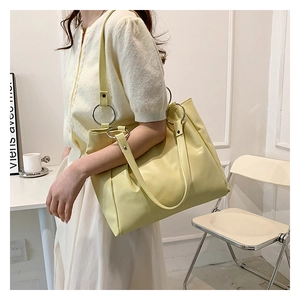 Detail of a cream faux leather tote bag showing the large silver ring strap connector