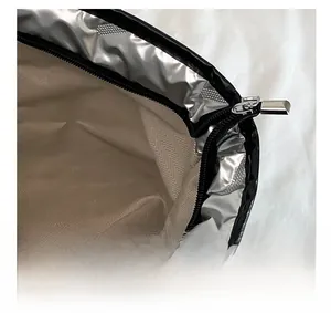 Close-up of silver metallic fabric edge and metal zipper with herringbone lining texture