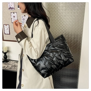 Detail of a black quilted tote bag showing its soft padded texture and glossy finish