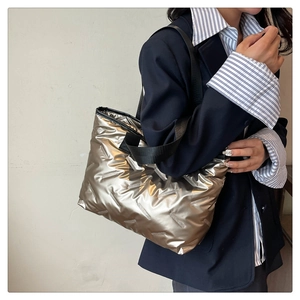 Detail of champagne gold quilted puffer tote bag with metallic finish and wide shoulder strap