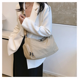 Sac bandoulière beige tendance avec sangle réglable porté par un mannequin au style chic