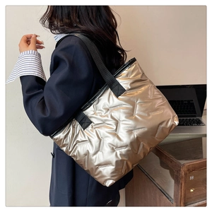 Close-up of champagne gold quilted tote bag with metallic sheen and black strap