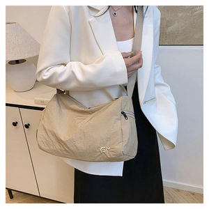 Close-up of beige nylon crossbody bag with textured fabric and metallic logo detail