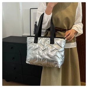 Detail of silver quilted tote bag with black nylon handles shown in a lifestyle setting