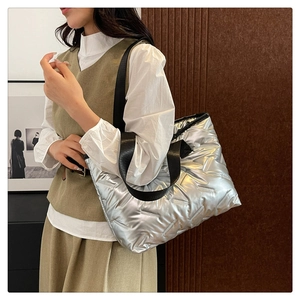 Detailed view of silver quilted tote bag with black strap and metallic finish on model