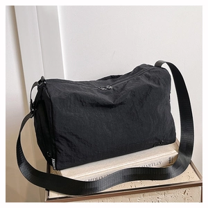 Détail d'un sac bandoulière en nylon noir avec étiquette fashion et sangle réglable