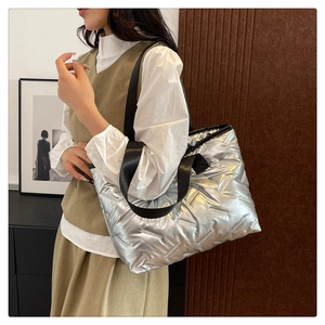 Detail view of metallic silver quilted tote bag with wide black shoulder strap for women