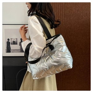 Side view of silver quilted tote bag with metallic finish and black nylon straps