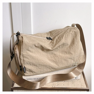 Détail d'un sac cabas en nylon beige avec texture plissée et large bandoulière réglable
