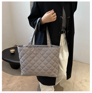 Gray quilted tote bag with diamond stitching shown in a stylish lifestyle setting
