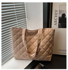 Detail of diamond quilted texture and wide shoulder strap on a beige tote bag