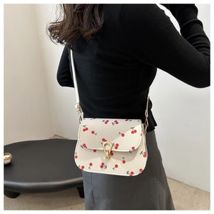 Detail of cherry print shoulder bag featuring gold horseshoe twist lock and adjustable strap