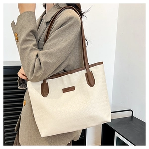Detail of star-embossed cream tote bag with brown straps worn by a female model