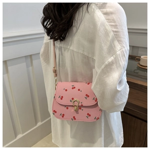 Detail of pink cherry print crossbody bag featuring a golden horseshoe clasp and PU leather