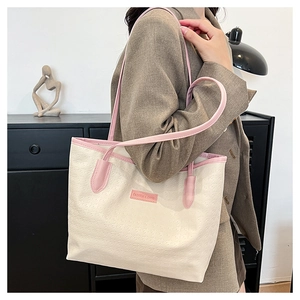 Detail of a contrast color tote bag with cream body, pink trim and embossed texture