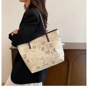 Detail of large tote bag showing brown leather handles and monogram pattern texture