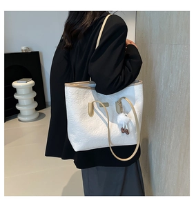 Detail of white tote bag with 3D embossed texture and cute fur ball pendant