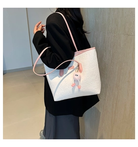 Détail d'un sac cabas blanc avec motifs de dessins animés et pendentif en peluche rose